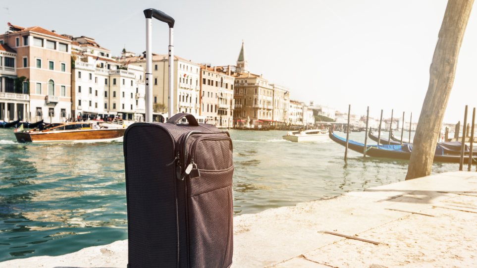 arouraios-image-small-suitcase-travel-urban-background-venice-italy-horizontal-toning-travel-vacation-concept